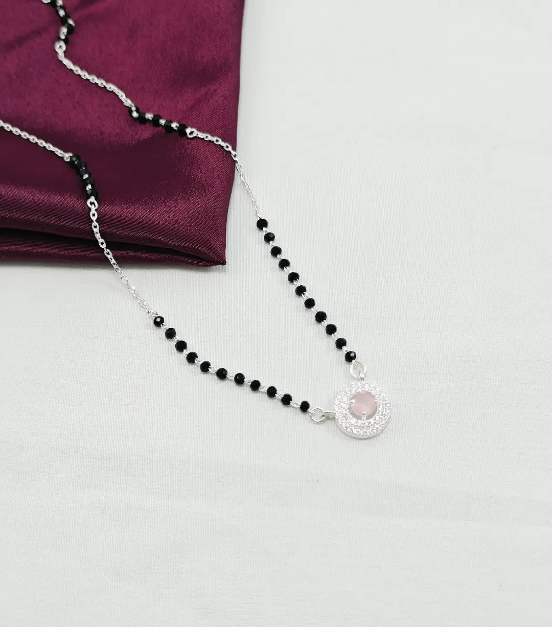 Black beaded necklace with a silver pendant on a white background